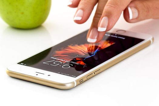 smart phone layar sentuh di atas meja sedang disentuh layarnya dengan jari seseorang
