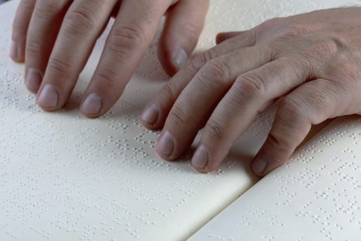 tangan sedang meraba huruf Braille